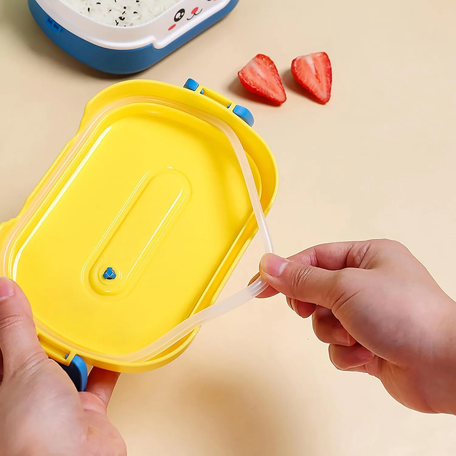 Hands removing the sealing ring from cute yellow bento box lid